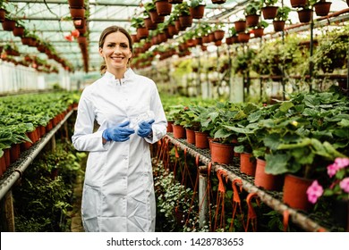 Portrait Of Happy Female Biologist Standing In A Plant Nursery And Looking At Camera. 