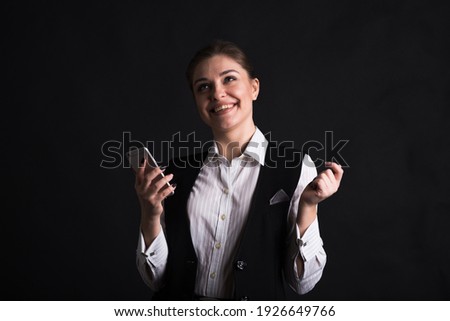Portrait of a happy female business woman who uses her smartphone in the studio on a black background