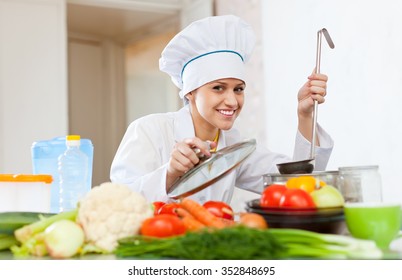 Portrait Of Happy Female Cook In White Works With Ladle