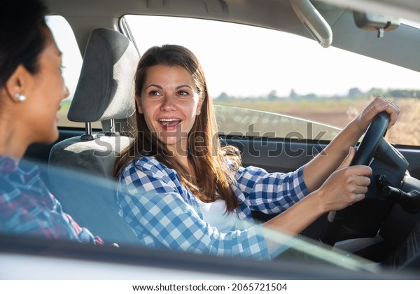 Portrait of\
happy female driver and her friend in\
car
