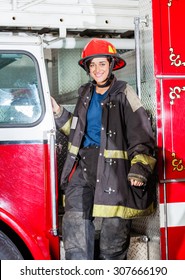 Portrait Of Happy Female Firefighter In Uniform Standing On Truck At Fire Station