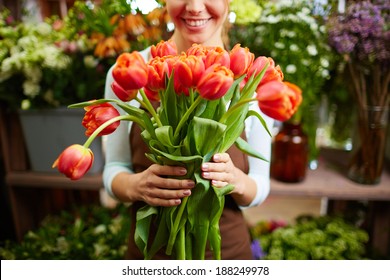 Portrait of happy female florist with bunch of red tulips looking at camera - Powered by Shutterstock