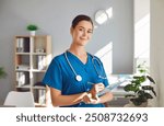 Portrait of happy female nurse or doctor at work. Beautiful young woman clinical nurse or physician in medical uniform holding pen and clipboard, standing in office, looking at camera and smiling