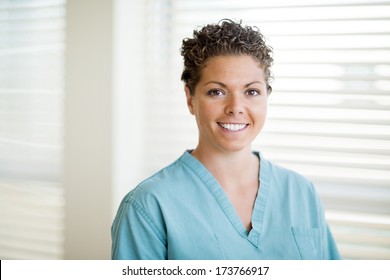 Portrait Of Happy Female Nurse In Scrubs At Clinic