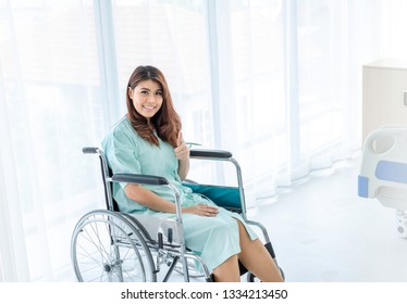 Portrait Of Happy Female Patient In Hospital Room With Thumbs Up Posture. The Sick Inpatient Smiling To Her Doctor And Nurse As She Recovering And Worry Free. Insurance Concept. Copy Space Provided. 