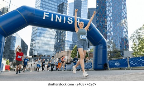 Portrait of Happy Female Runner Participating in a Marathon. Athletic Female Crossing the Finish Line, Celebrating, Raising Hands in the Air - Powered by Shutterstock