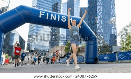 Portrait of Happy Female Runner Participating in a Marathon. Athletic Female Crossing the Finish Line, Celebrating, Raising Hands in the Air
