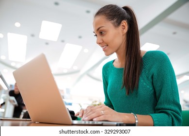 Portrait Of A Happy Female Student Using Laptop Computer In University