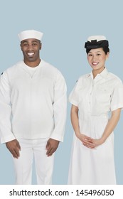 Portrait Of Happy Female US Navy Officer With Male Sailor Over Light Blue Background