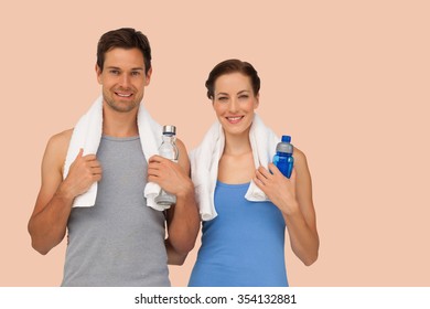 Portrait of a happy fit couple with water bottles against orange background