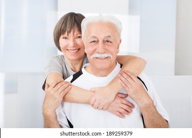Portrait of happy fit senior couple embracing at gym