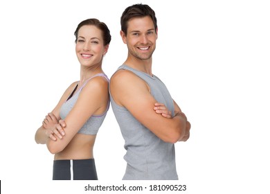 Portrait of a happy fit young couple with hands crossed over white background