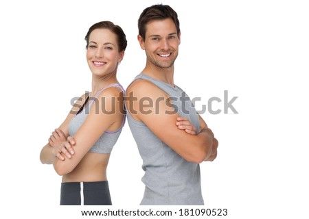 Portrait of a happy fit young couple with hands crossed over white background