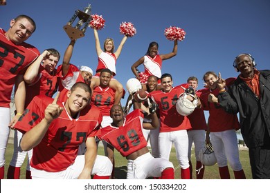 Portrait of happy football team with cheerleaders and coach celebrating success on field