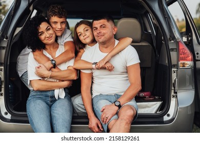 Portrait of Happy Four Caucasian Members Family Sitting in Trunk of Minivan Car, Mother and Father with Two Teenage Children, Son and Daughter Having Weekend Outdoors