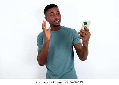 Portrait Of Happy Friendly Young Handsome Man Wearing Green T-shirt Over White Background Taking Selfie And Waving Hand, Communicating On Video Call, Online Chatting.