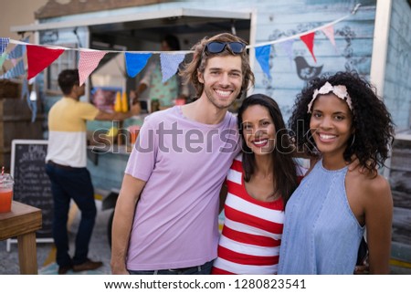 Portrait of happy friends with arms around near food truck