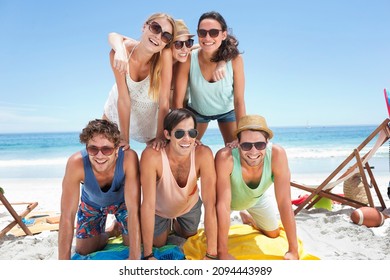 Portrait of happy friends forming pyramid on beach - Powered by Shutterstock