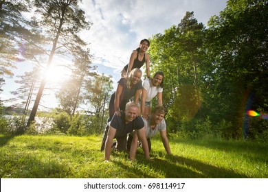 Portrait Of Happy Friends Making Human Pyramid On Field