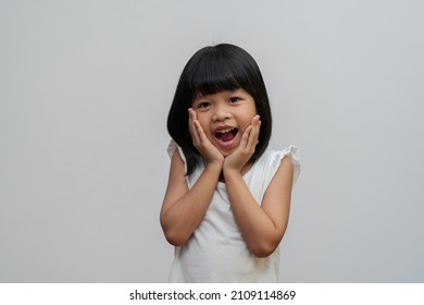 Portrait Of Happy And Funny Asian Child Girl On White Background, A Child Looking At Camera. Preschool Kid Dreaming Fill With Energy Feeling Healthy And Good Concept