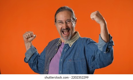 Portrait Of Happy Funny Mature Man Showing Muscles Isolated On Solid Orange Background.