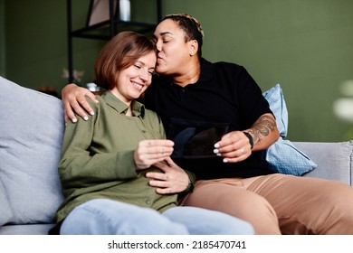 Portrait Of Happy Gay Couple With Pregnant Young Woman Looking At Ultrasound Image Of Baby, Same Sex Family