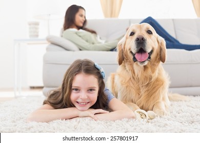 Portrait of happy girl with dog lying on rug while mother relaxing at home
