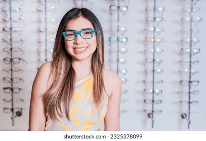 Portrait of happy girl in glasses in an eyeglasses store. Smiling happy girl in eyeglasses with store eyeglasses background
