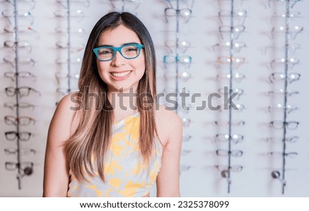 Portrait of happy girl in glasses in an eyeglasses store. Smiling happy girl in eyeglasses with store eyeglasses background