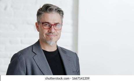 Portrait of happy good looking older businessman in glasses wearing jacket, smiling in front of white background with copy space.  .