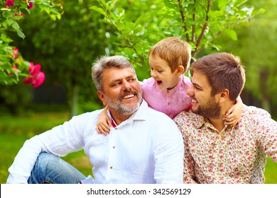 Portrait Of Happy Grandpa, Father And Son In Spring Garden