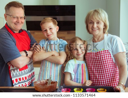 Portrait of happy grandparents have fun with their grandchildren preparing chocolate muffins in modern kitchen