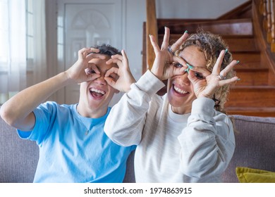 Portrait of happy grown-up teenager man posing with mother have fun at home together, young mom make funny gestures with adult son indoor - Shutterstock ID 1974863915