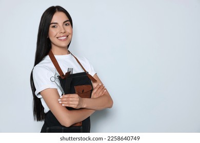 Portrait of happy hairdresser with professional scissors and comb on light background, space for text - Powered by Shutterstock