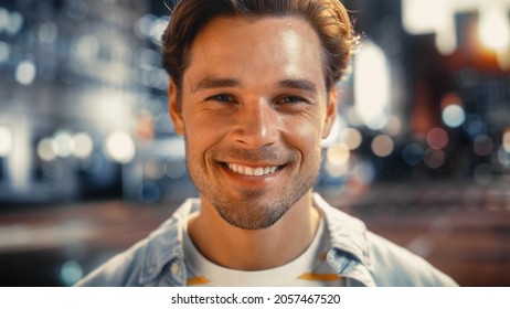 Portrait Of A Happy Handsome Young Man In Casual Clothes Standing On The Street At Sunset. Stylish Male Model In Big City Living The Urban Lifestyle. Background With Office Buildings And Billboards.