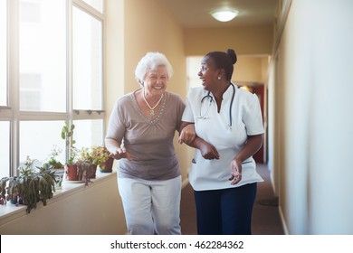 Portrait Of Happy Healthcare Worker And Senior Woman Walking Together. Senior Patient Having Fun With Her Home Caregiver.