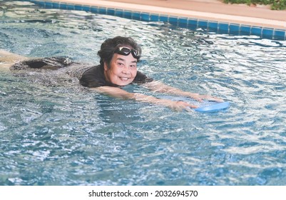 Portrait of happy and healthy Asian senior woman swimming with kickboard in a swimming pool. Smiling old woman swimming with inflatable board in swimming pool.  Elderly active lifestyle. - Powered by Shutterstock