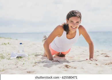 Portrait Of Happy Healthy Woman Doing Push Up At The Beach