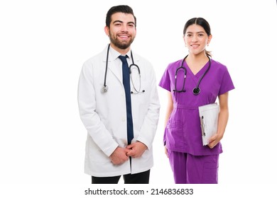 Portrait Of A Happy Hispanic Doctor And Medical Nurse Smiling And Looking At The Camera Against A White Background