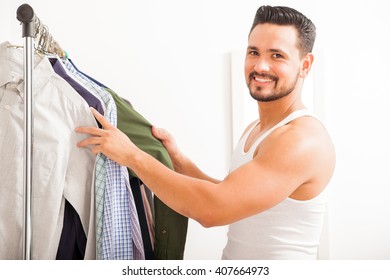 Portrait Of A Happy Hispanic Young Man Choosing What To Wear And Getting Dressed In His Bedroom