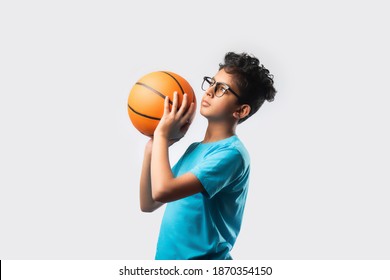Portrait of happy Indian asian boy playing or holding basketball against white background