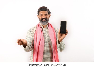 Portrait Of An Happy Indian Bearded Farmer Man In Rural India Concept. Funky Expressions White Background. Cheerful Farmer Showing Mobile Phone Screen And  Seeds In Other Hand Portraying Prosperity.