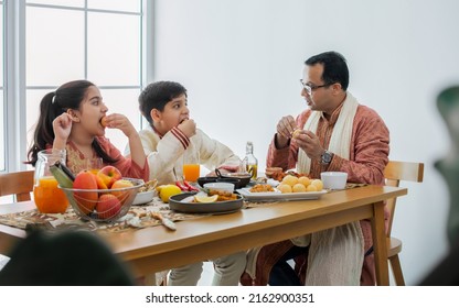 Portrait Of Happy Indian Family, Father, Son, Daughter Wearing Traditional Clothes, Sitting At Table Together For Breakfast, Lunch Or Dinner, Eating And Fun Talking With Warm. Lifestyle Concept