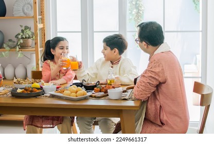 Portrait of happy Indian family, father, son, daughter wearing traditional clothes, sitting at table together for breakfast, lunch or dinner, eating and fun talking with warm. Lifestyle Concept - Powered by Shutterstock