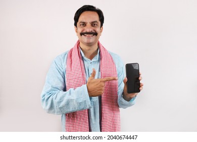 Portrait of happy Indian farmer man in rural India concept. Funky expressions white background. Cheerful farmer showing mobile phone screen and using technology. - Shutterstock ID 2040674447