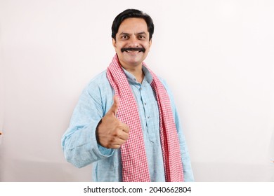 Portrait of an happy Indian farmer in rural India concept. Standing in the white background, the passionate farmer full of enthusiasm shows thumbs up as a metaphor of achievement and accomplishments.
