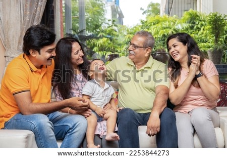 Portrait of Happy indian joint family sitting together at home. Asian senior and young couple with their kids spent time and having fun.