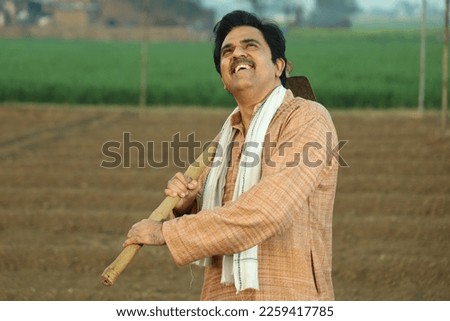 Portrait of happy Indian rural farmer standing in the field looking towards the sky holding a weeding hoe in hands. Foto stock © 