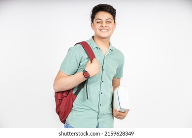 Portrait of happy indian teenager college or school boy with backpack holding books, isolated on white background. Smiling young asian male kid looking at camera. - Shutterstock ID 2159628349