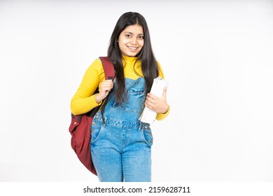 Portrait of happy indian teenager college or school girl with backpack holding books, isolated on white background. Smiling young asian female kid looking at camera.